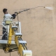 Bezdotyková aplikácie a čistenie fasády - Profesionál z Umyjemto umýva znečistenú fasádu za pomocou zvdihací plošiny